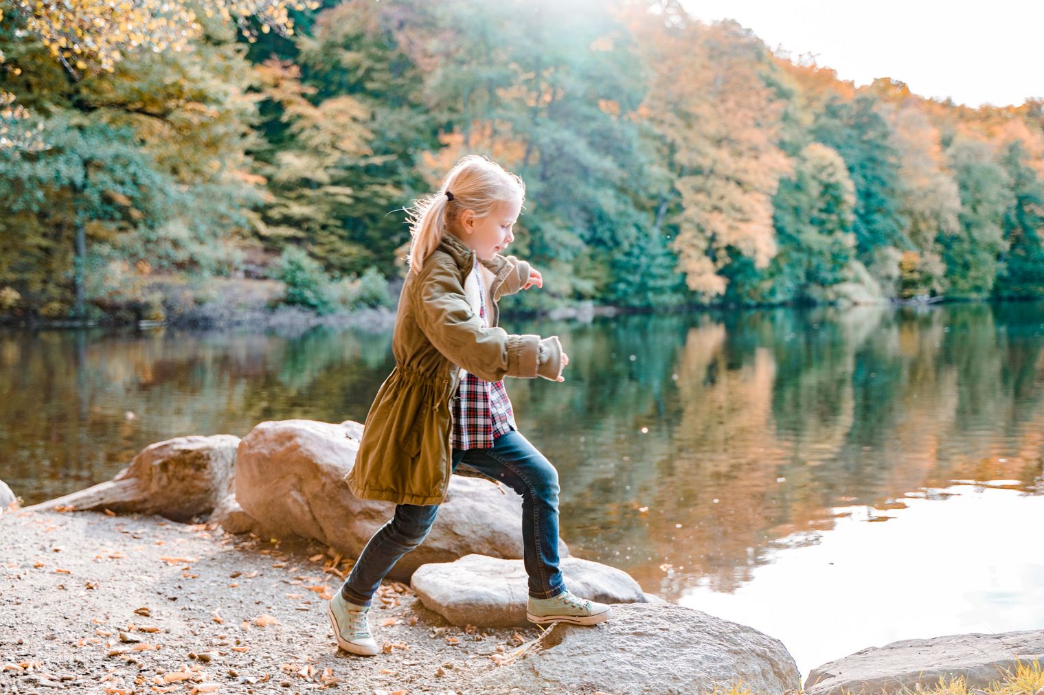 Ein Mädchen klettert am Wasser auf Steinen