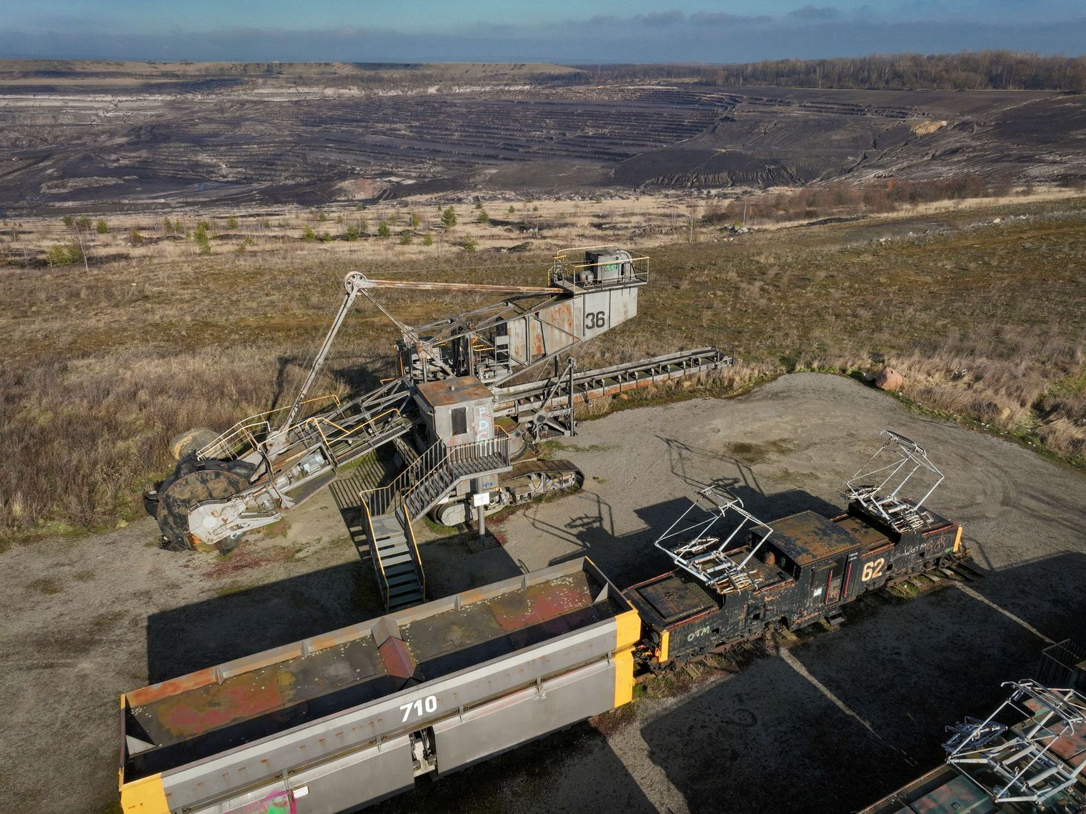 Außer Betrieb genommener Schaufelradbagger und im Hintergrund ist ein Tagebau erkennbar